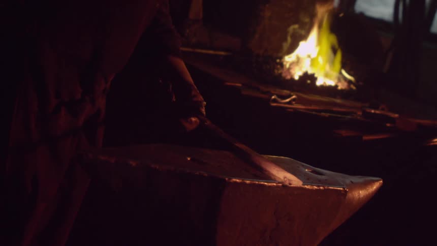 A blacksmith pounding a blade