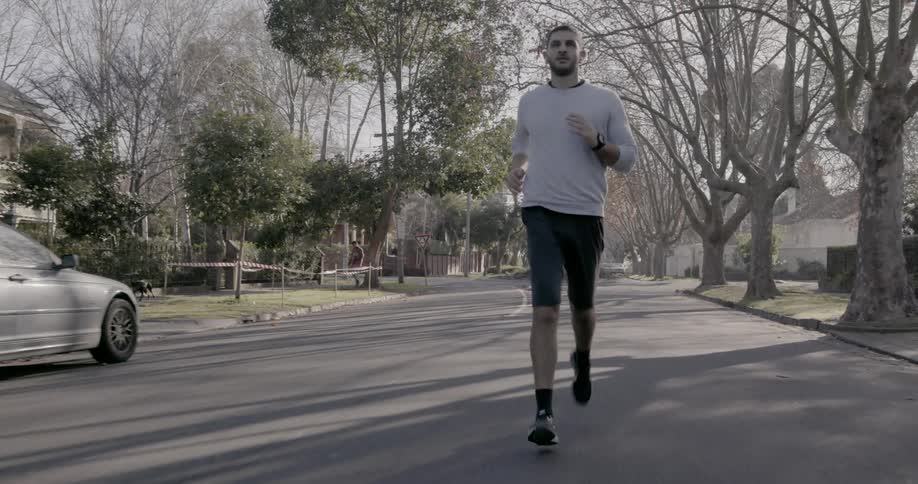 A man is running down the street on a sunny day