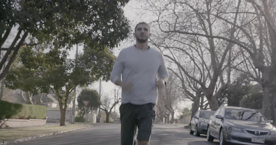 A man is jogging down the middle of the street