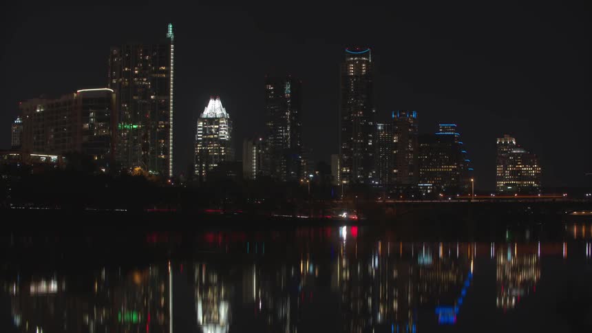 Time lapse of cars moving on a road in front of a city at night