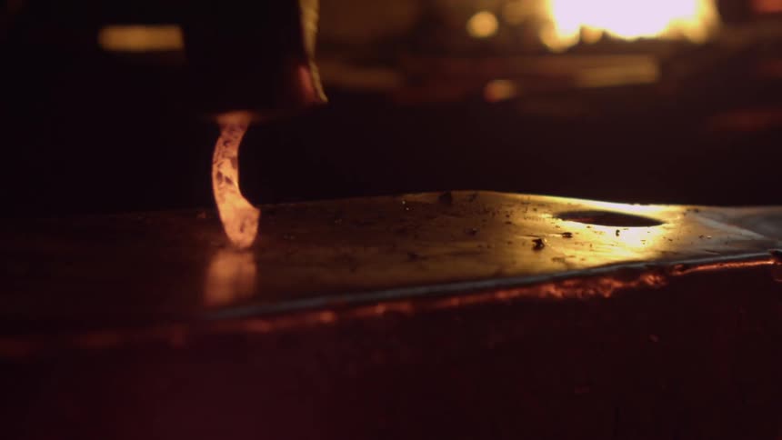 A blacksmith hammers a piece of heated metal