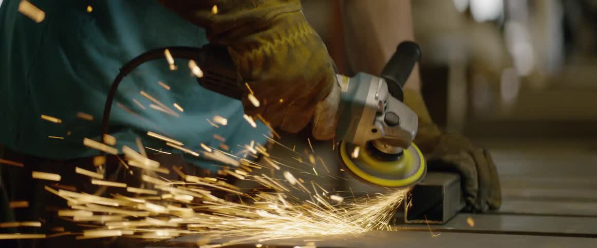 Sparks fly around a man using a power tool