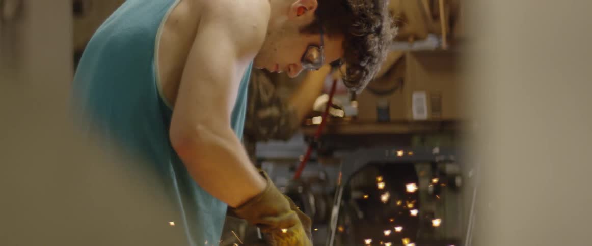 A metal worker grinds steel in a workshop