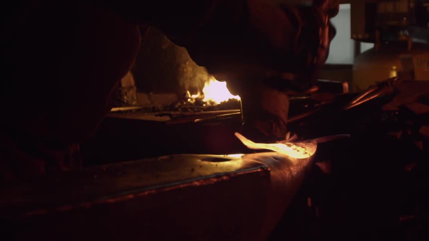 A person hammers heated metal into shape