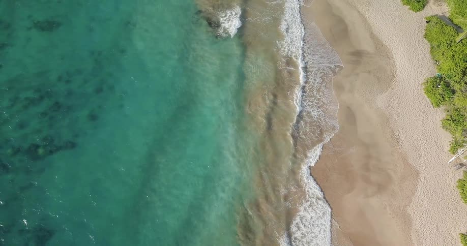 The blue clear water crashes against the shore