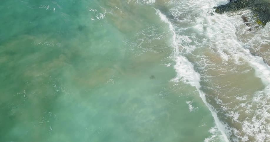 A clean blue ocean waves are crashing onto the beach