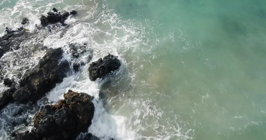 The water splashes and covers the rocks by the shore