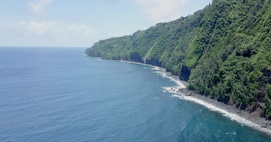 Waves roll onto the shore of a beach at the base of a cliff