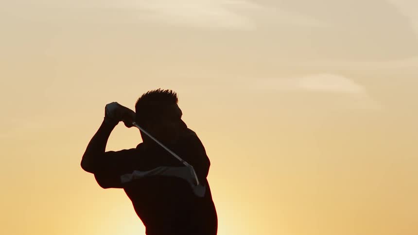 A man winds up and swings a golf club