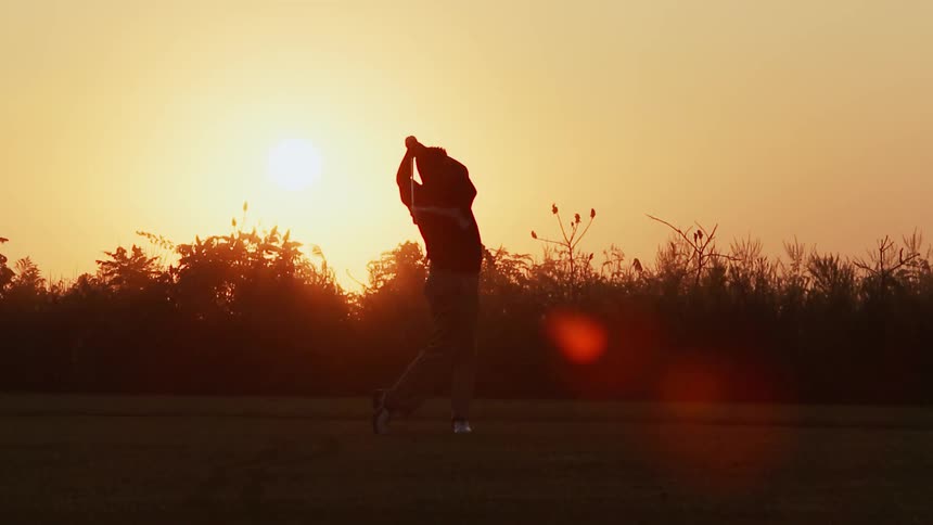 A man drives the golf ball at dawn