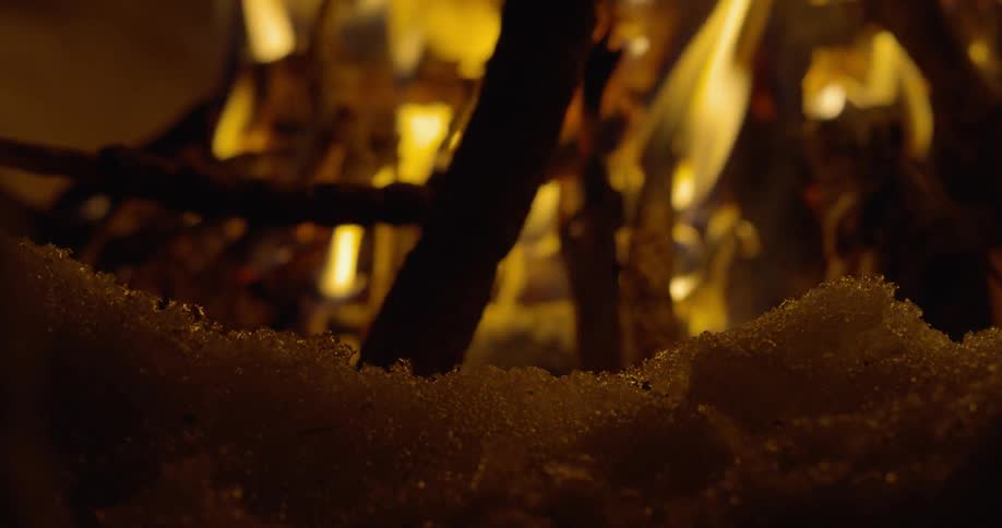 A camp fire burns outside at night in the winter