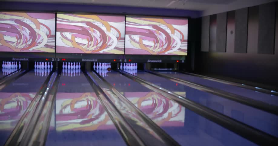 A man celebrates with friends after bowling a strike in a bowling alley