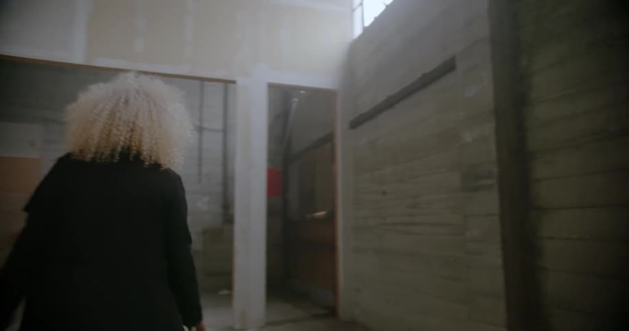 A woman is walking in an empty warehouse building during the day