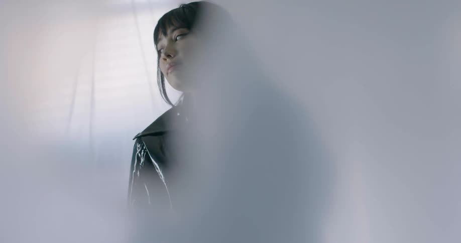 A woman is dancing wearing a black latex jacket