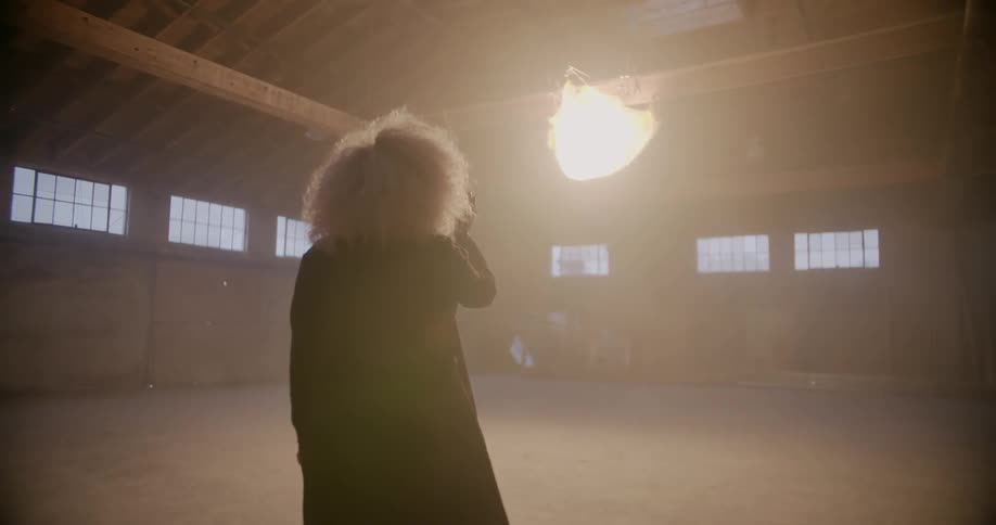 A woman walks towards a glowing object hanging from a ceiling