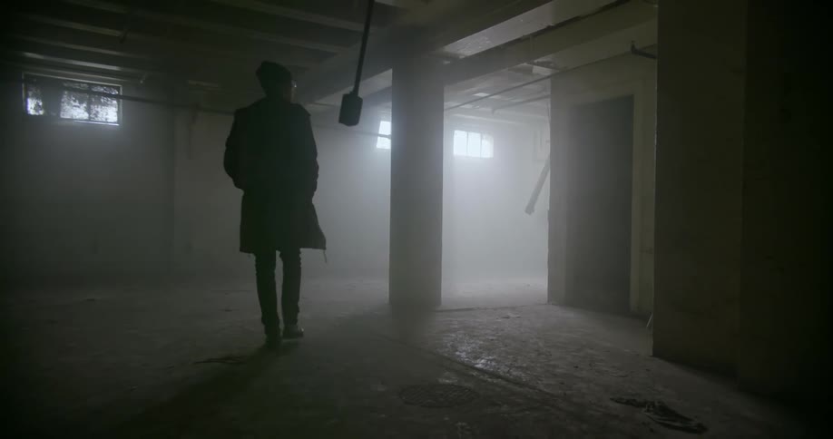 A man walks slowly through the basement