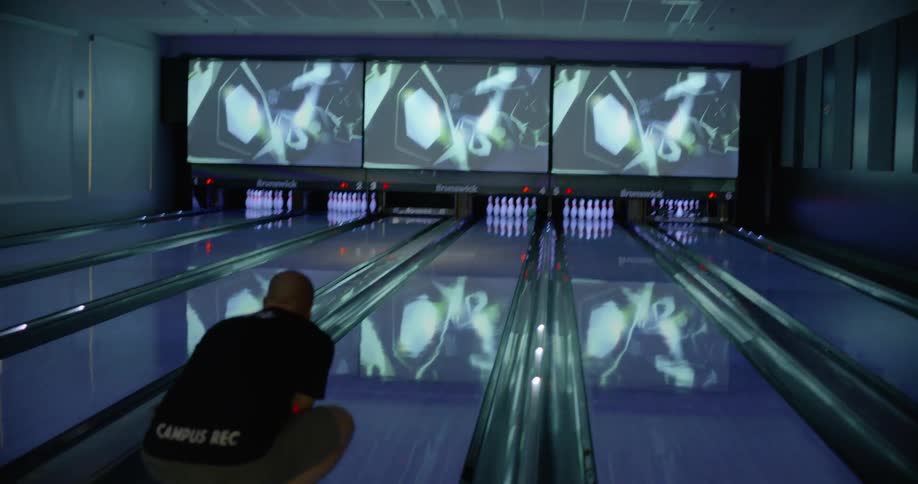 A man throws the ball towards the bowling pins