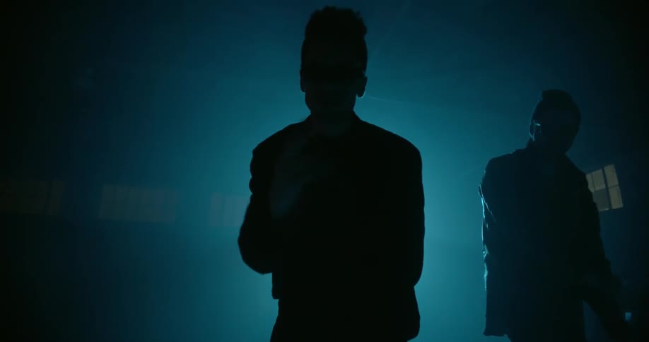 Men dance in front of a spotlight