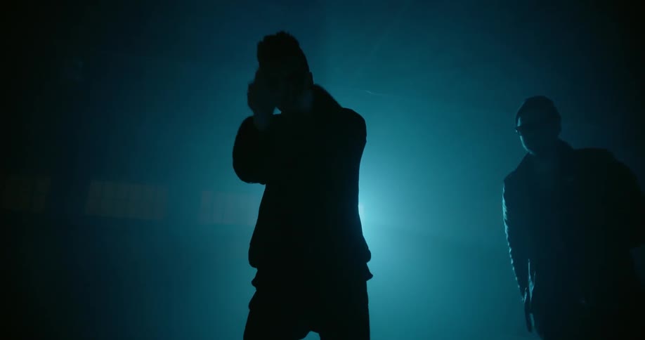 Men dance in front of a spotlight