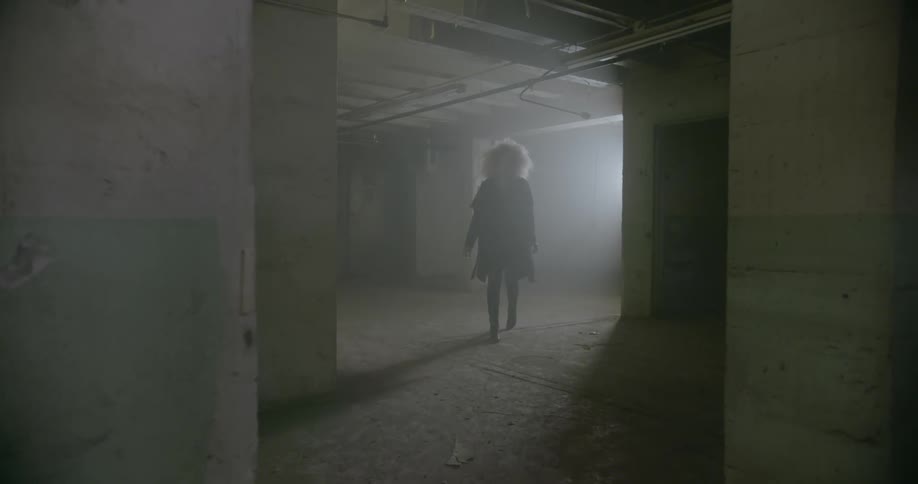A woman walks through an empty concrete room