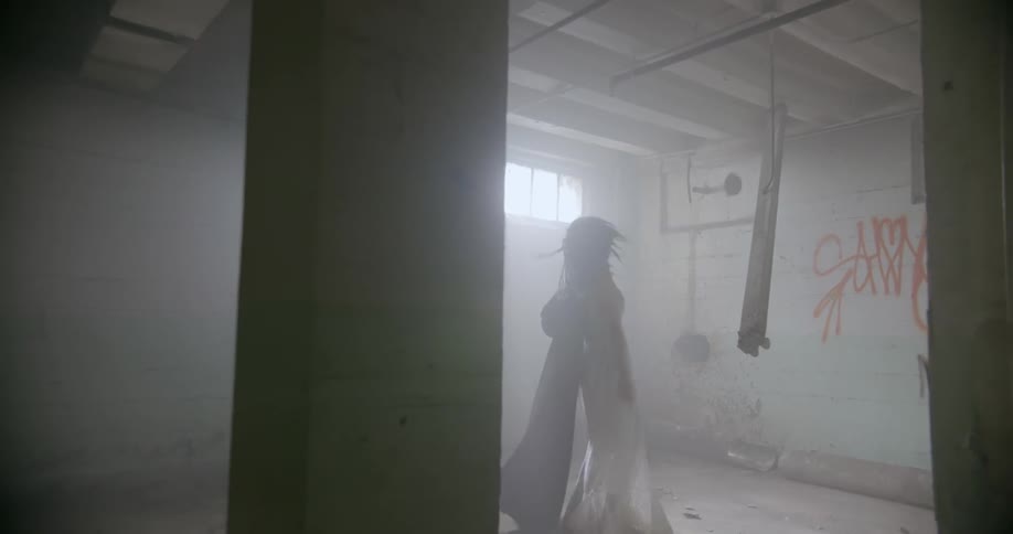 A woman is dancing inside an abandoned building during the day