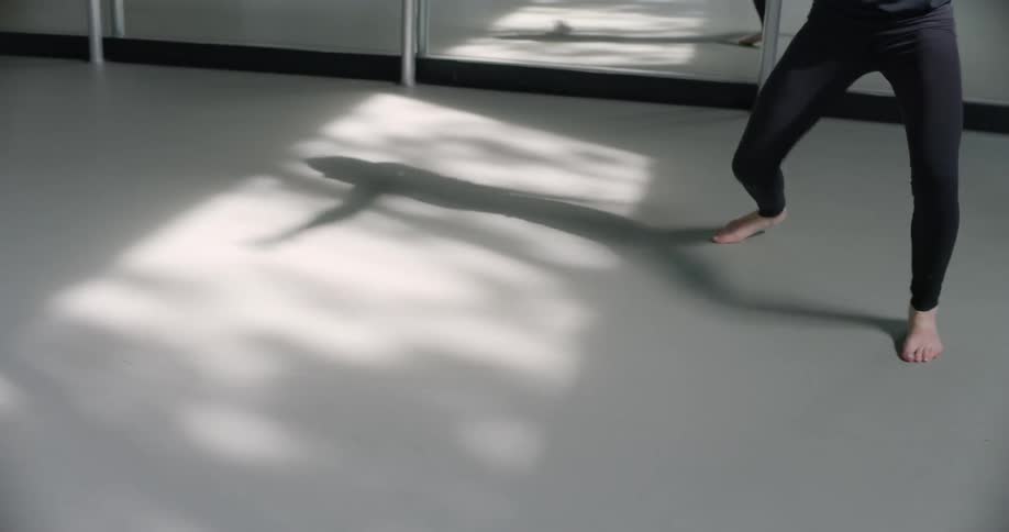 A woman is rehearsing a dance in a dance studio during the day