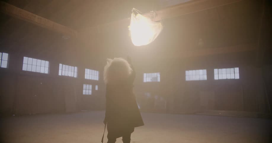 Woman walks towards a glowing object hanging from a ceiling