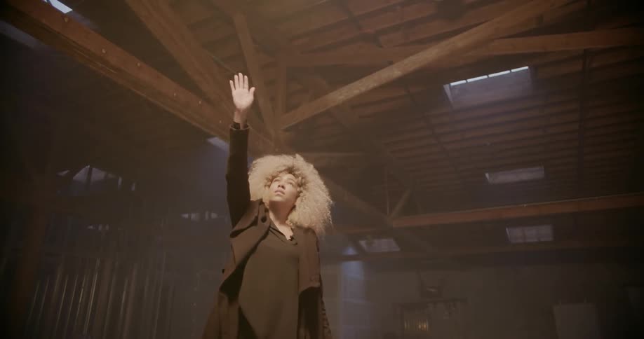 A woman raises her hand up towards the ceiling