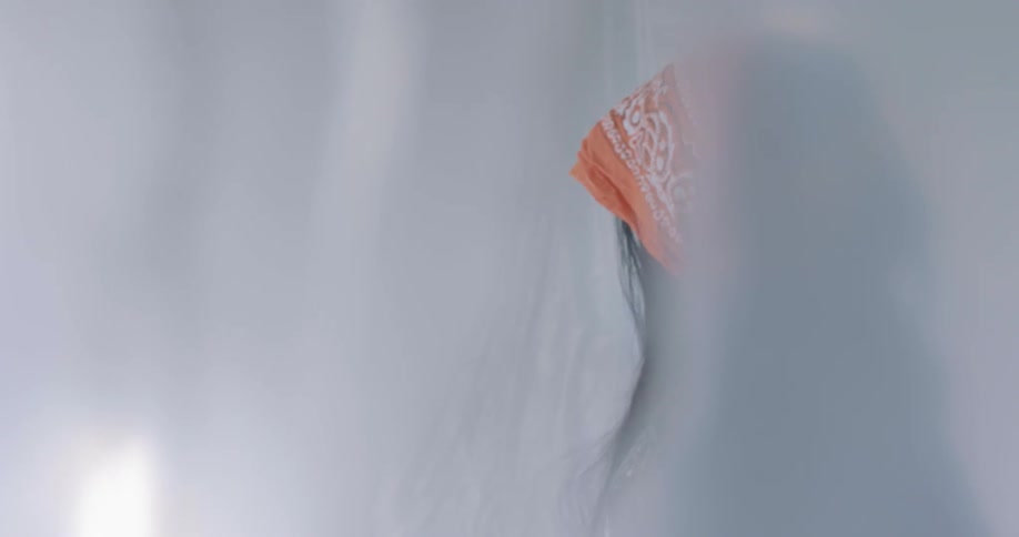 A woman wearing a bandanna is dancing around in her room