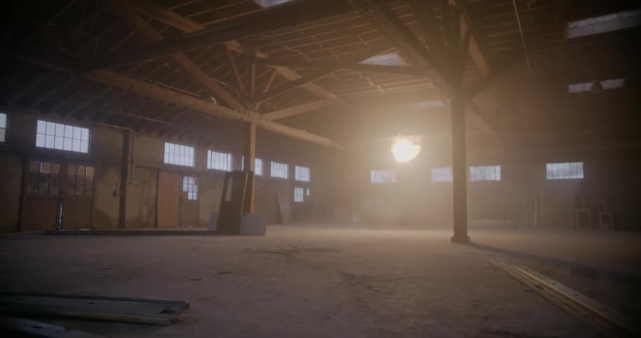 A ball of burning light is glowing near the ceiling of an empty warehouse building