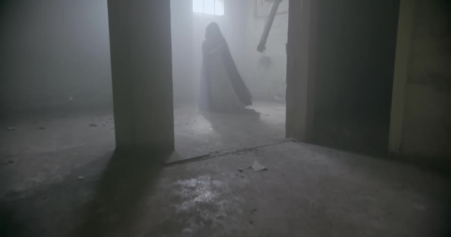 A person is wearing a robe and doing some sort of movement in an abandoned building