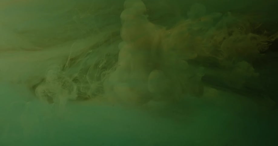 The green liquid is swirling with clouds in a dark container