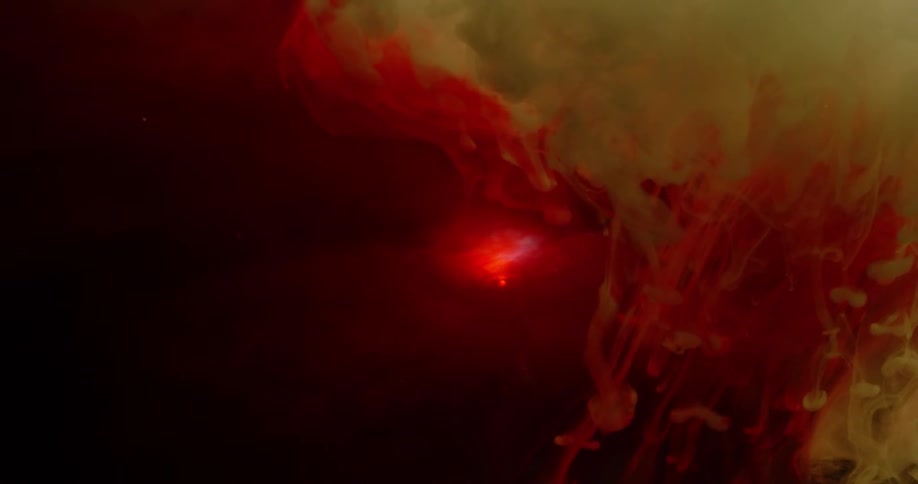 Red and yellow dye swirl in liquid