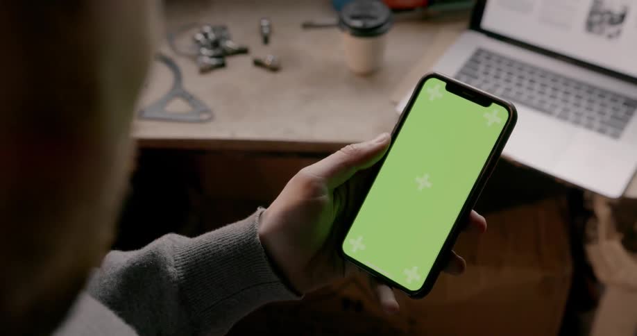 A man looks at a green grid on his phone