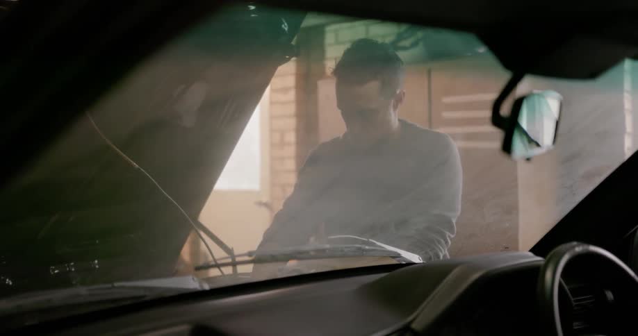 A man is working under the hood of a car