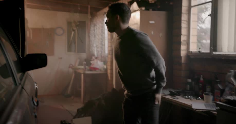 A man uses a laptop in a garage