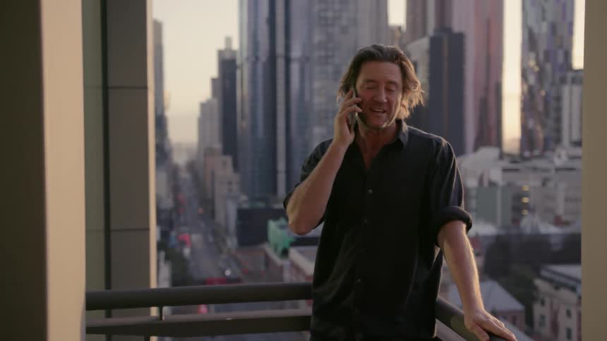 A man talks on the phone on his balcony