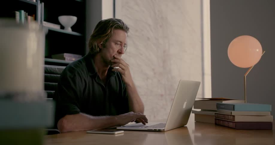 A man is using his laptop at his desk