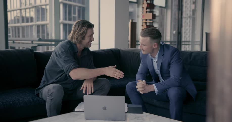 Two men look at a laptop and talk