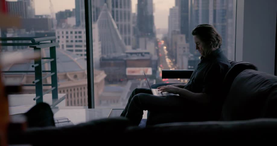 Man sits on couch on types on laptop in city