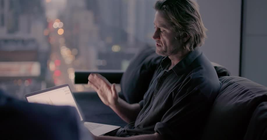 A man talks as he points to his laptop