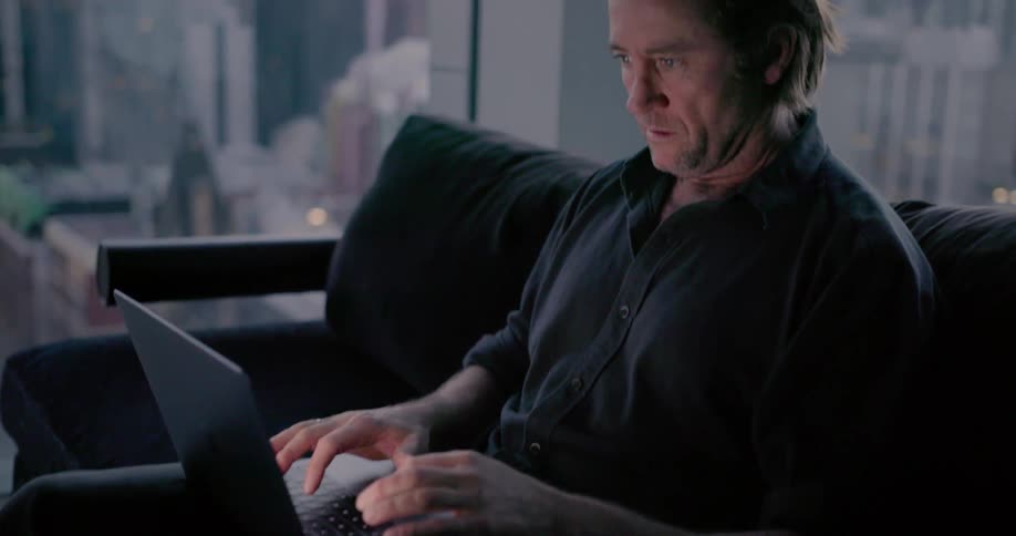 Man sits on office couch and types on laptop