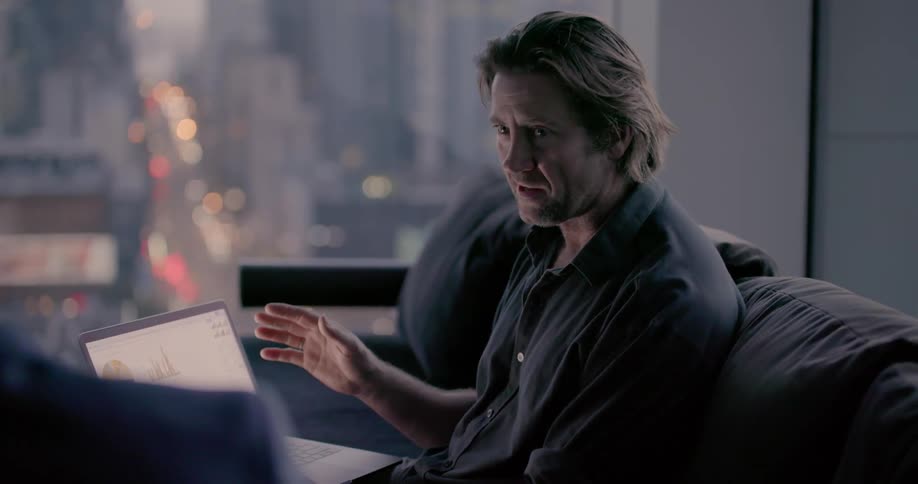 A man talks with a friend while pointing towards a laptop