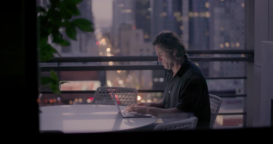 Man types on his laptop at a table