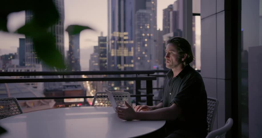 A man is sitting at the table near a huge window