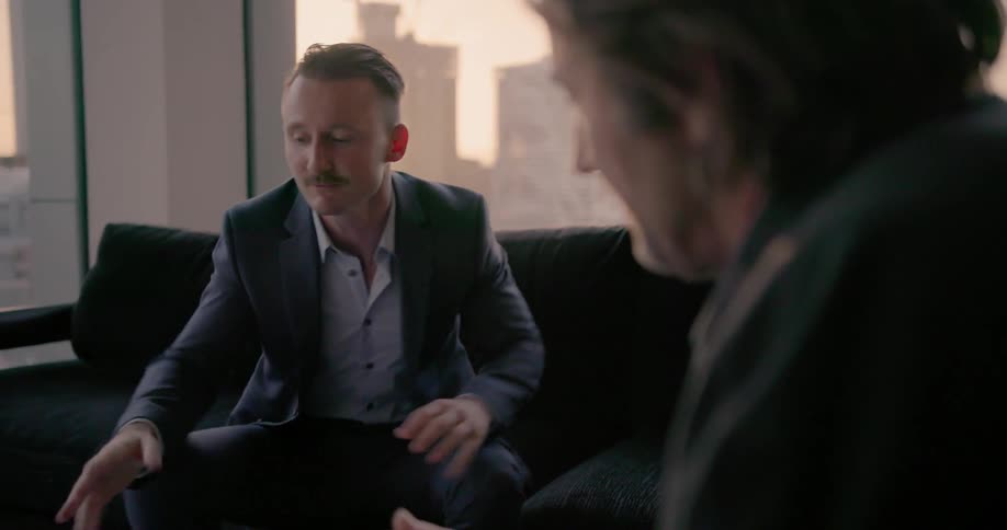 Two people talk together on a couch looking at a laptop