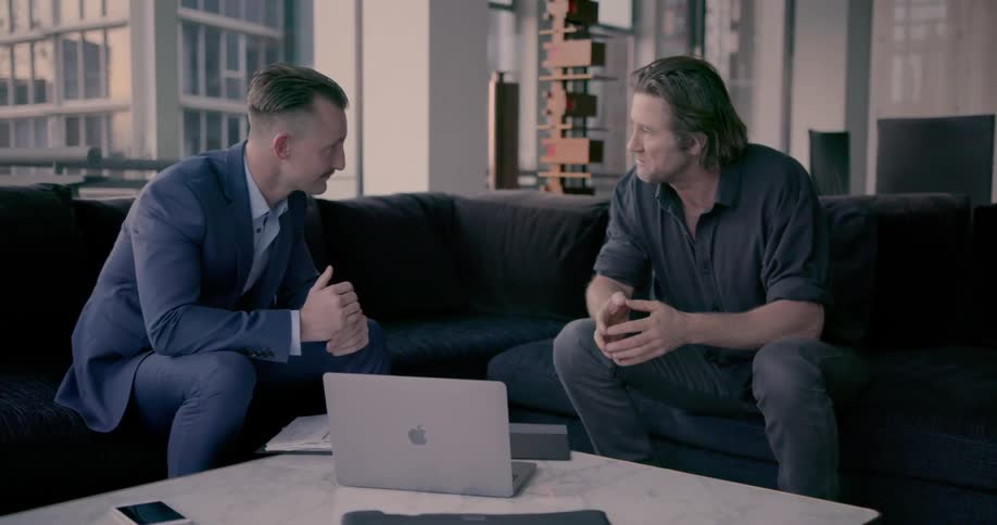 Two men shake hands and have a conversation