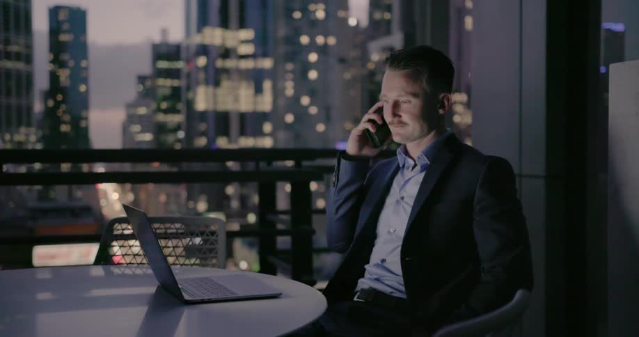 Man works on a laptop on a city balcony