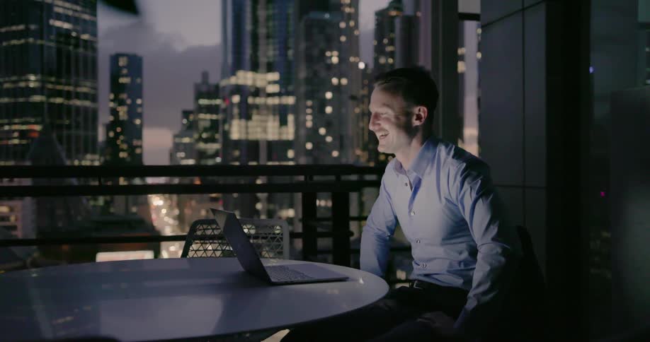 Man works on a laptop on a city balcony