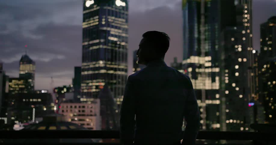 A man is looking out over the city at dusk